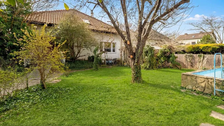 Großer Garten mit Rasenfläche, altem Baumbestand und einem kleinen Pool hinter dem Haus.