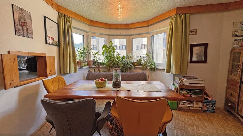 Gemütlicher Essbereich mit Holztisch, bequemen Stühlen und Blick ins Grüne durch die Fensterfront.