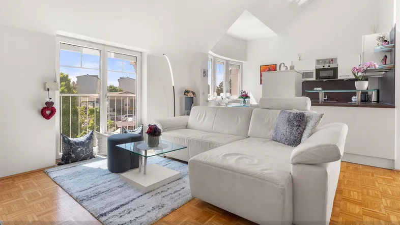 Helles Wohnzimmer mit weißem Sofa, Parkettboden und Zugang zu einem französischen Balkon.