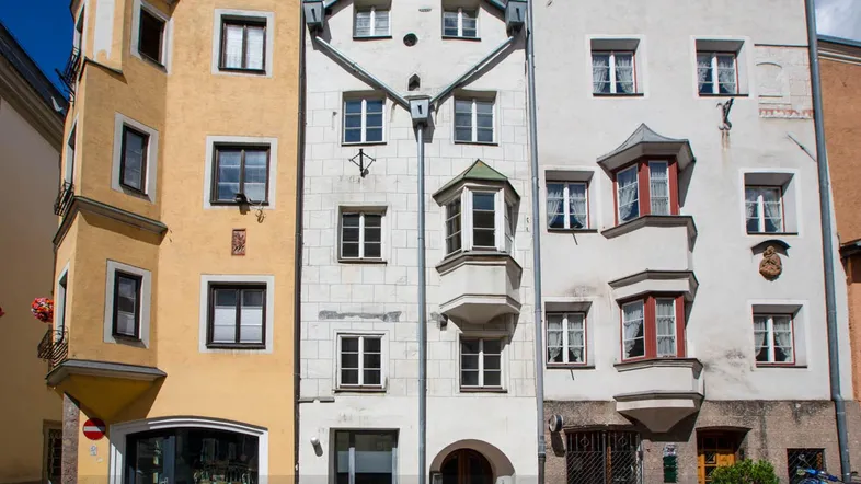 Historische Gebäude mit traditioneller Architektur und Erkern in einer engen Gasse.