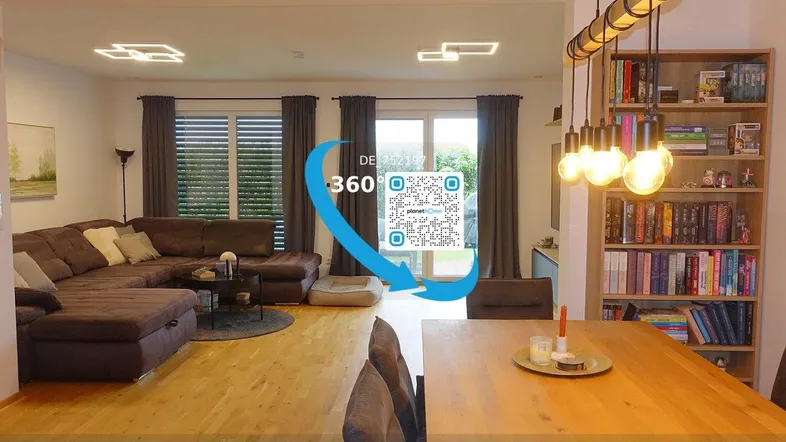 Heller, offener Wohn- und Essbereich mit Holzboden, großem Sofa, Esstisch und modernen Leuchten.