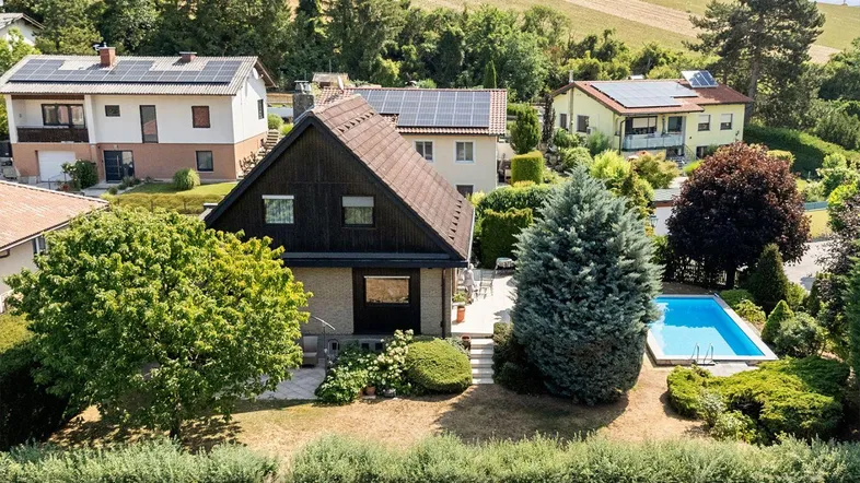 Luftaufnahme eines Hauses mit Pool, umgeben von viel Grün und weiteren Wohnhäusern in ländlicher Umgebung.