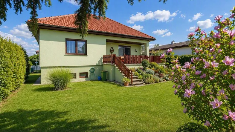 Gepflegter Garten mit blühenden Sträuchern und Blick auf das Einfamilienhaus mit Terrasse.