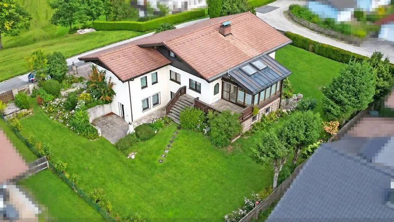 Luftaufnahme eines Einfamilienhauses mit großem Garten und Wintergarten in ländlicher Umgebung.