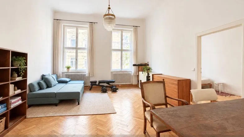 Helles Wohnzimmer mit Fischgrätparkett, hohen Fenstern und einem Bereich für Fitness und Essen.