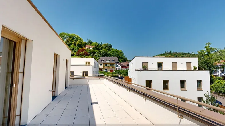 Große, helle Terrasse mit Blick auf die umliegenden Gebäude und viel Grün.