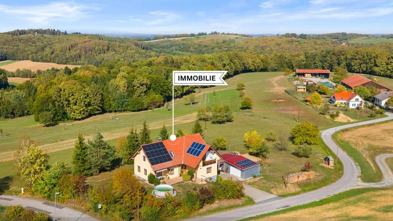 Luftaufnahme des Hauses mit Solaranlage, umgeben von grüner Landschaft und Wäldern.