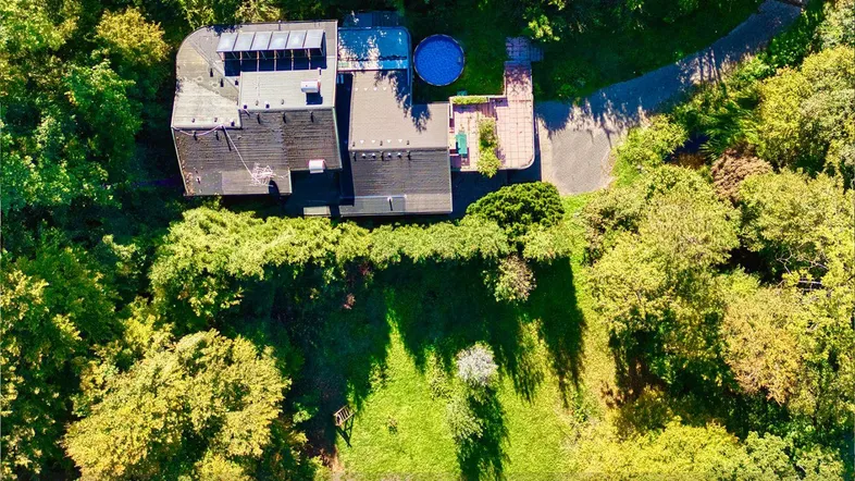 Luftaufnahme eines Hauses mit Solarpaneelen auf dem Dach und einem kleinen Pool im Gartenbereich.