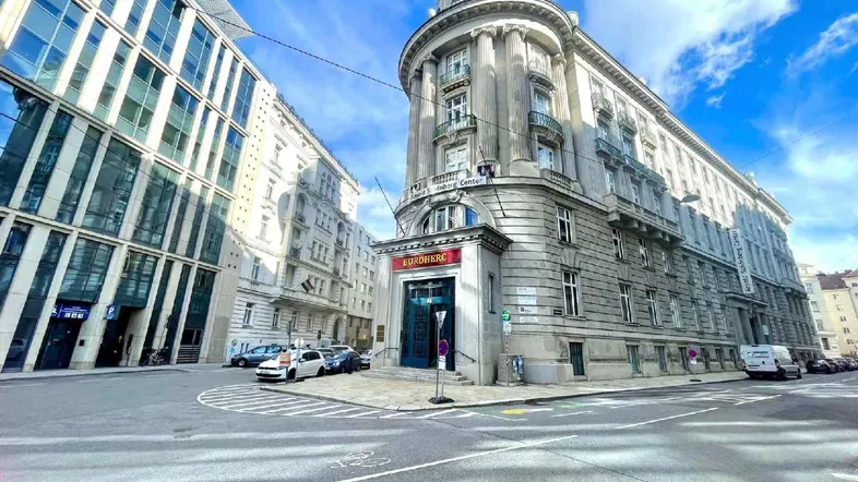 Historisches Eckgebäude mit klassischer Architektur und modernen Glasfassaden im städtischen Umfeld.