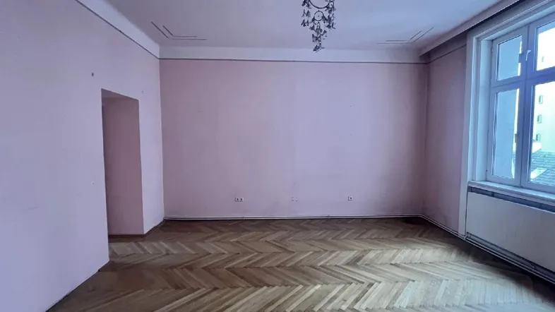 Geräumiges Zimmer mit Fischgrätparkett und rosa Wänden, bereit für individuelle Gestaltung.