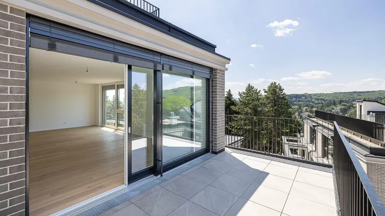 Balkon mit Fliesenboden und weitem Blick über die Landschaft und eine entfernte Stadt.
