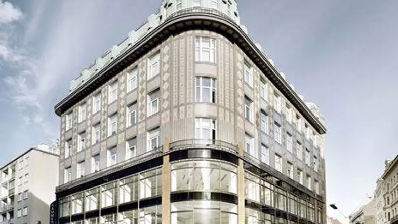 Historisches Gebäude mit markanter Architektur und moderner Glasfassade im Erdgeschoss in urbaner Umgebung.