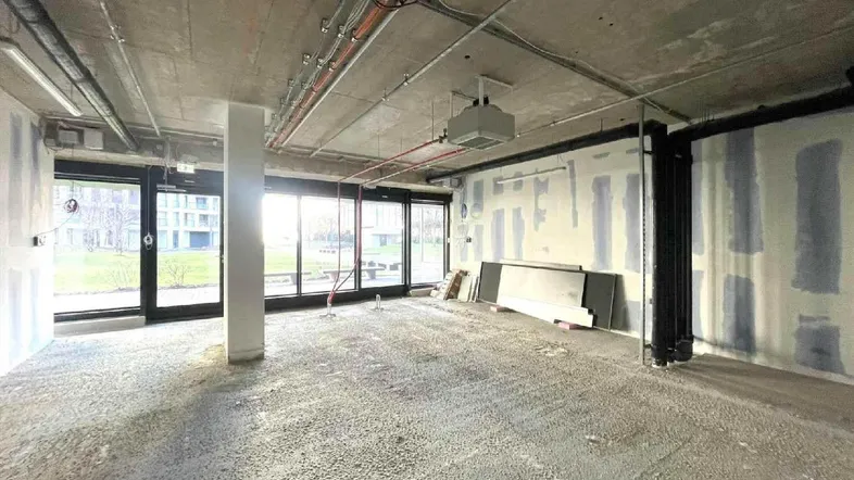 Großer, unfertiger Innenraum mit hohen Decken und großen Fenstern, die viel Tageslicht hereinlassen.