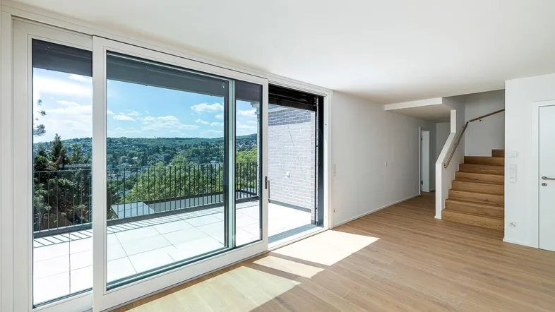 Helles Wohnzimmer mit großen Schiebetüren, Holzboden und weitem Ausblick ins Grüne.