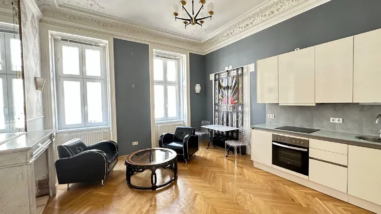 Geräumiger Wohn-Essbereich mit offener Küche, Fischgrätparkett und Stuckdecke in einem Altbau.