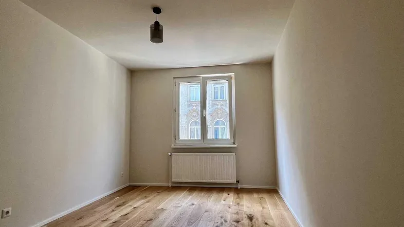 Helles Zimmer mit neuem Holzparkettboden und Blick auf die gegenüberliegende Fassade.
