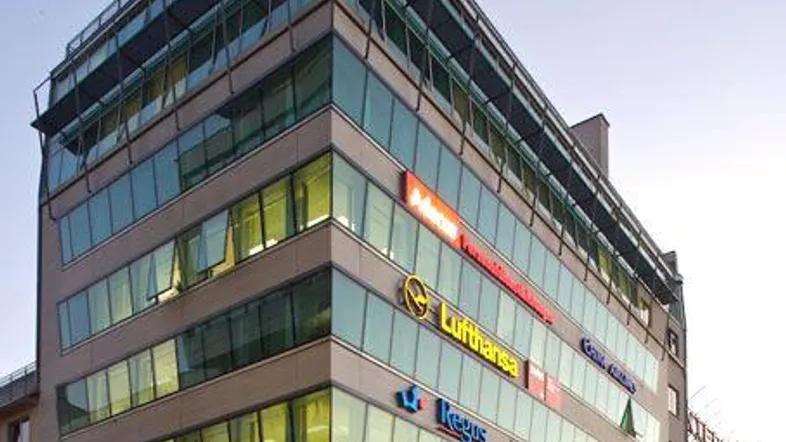 Modernes Bürogebäude mit Glasfassade und mehreren Etagen, beleuchtet von der Abendsonne.
