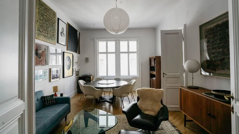 Helles Wohn- und Esszimmer mit Parkettboden, modernen Möbeln und einer Kunstgalerie an der Wand.