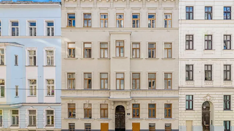 Historisches Mehrfamilienhaus mit klassischer Fassade und vielen Fenstern in einer städtischen Umgebung.
