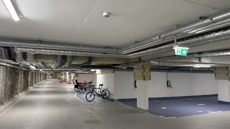Moderne Tiefgarage mit Fahrradabstellplätzen, Parkflächen und Ladestationen für Elektrofahrzeuge.
