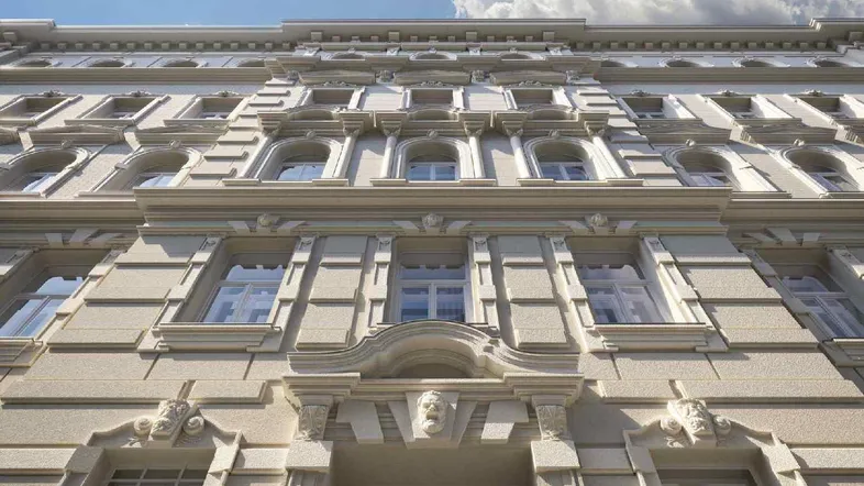Detailansicht der historischen Fassade mit aufwendigen Stuckelementen und großen Fenstern.