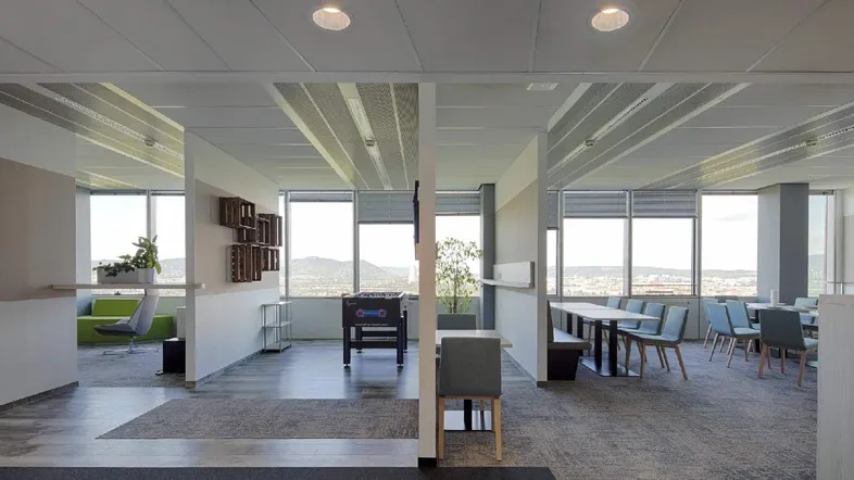 Moderner Bürobereich mit Tischfußball, Sitzgelegenheiten und weitem Ausblick auf die Landschaft.