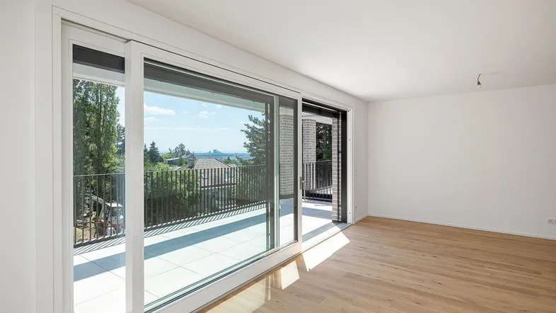 Geräumiger, heller Wohnraum mit Holzboden und Schiebetüren zum Außenbereich.