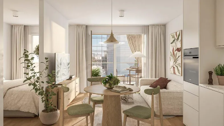 Kompaktes Studio-Apartment mit offener Küche, Essbereich und Zugang zu einem Balkon.