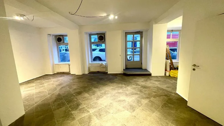 Heller Geschäftsraum mit großen Fenstern zur Straße und Fliesenboden, ideal für Ladenlokal.