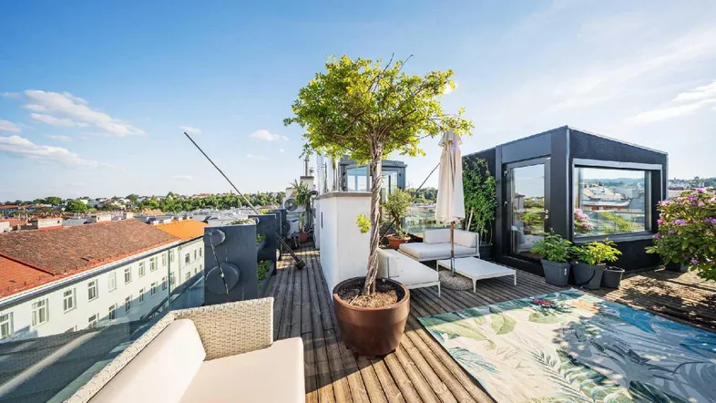 Geräumige Dachterrasse mit bequemen Loungemöbeln, Pflanzen und weitem Blick über die Stadt.