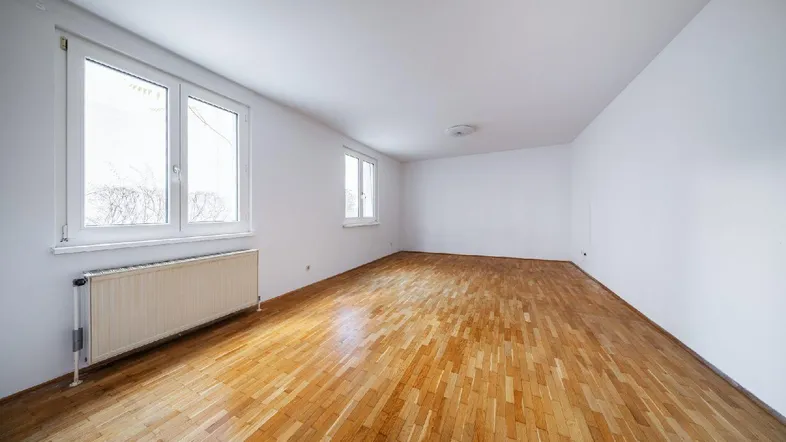Helles, leeres Zimmer mit Parkettboden und großen Fenstern, bereit zur individuellen Gestaltung.