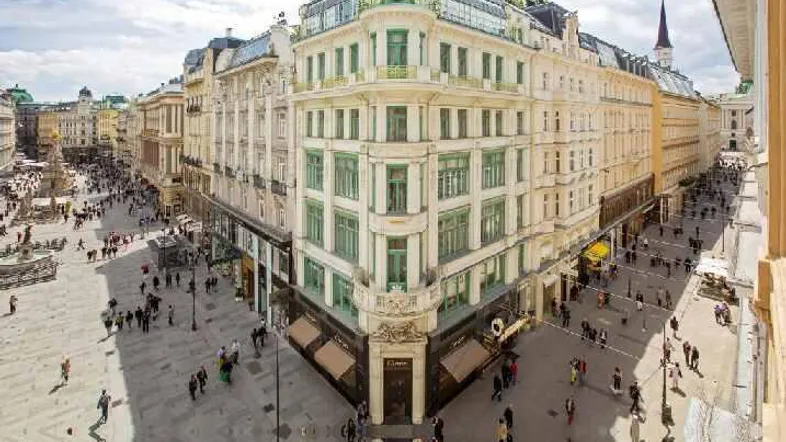 Panoramablick auf eine belebte Stadtkreuzung mit beeindruckenden historischen Gebäuden und moderner Architektur.