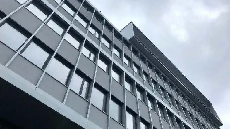 Moderne Fassade eines Bürogebäudes mit zahlreichen Fenstern unter einem bewölkten Himmel.