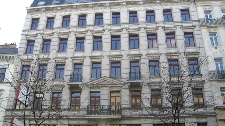 Klassische Fassade eines Mehrfamilienhauses mit vielen Fenstern und dekorativen Elementen.