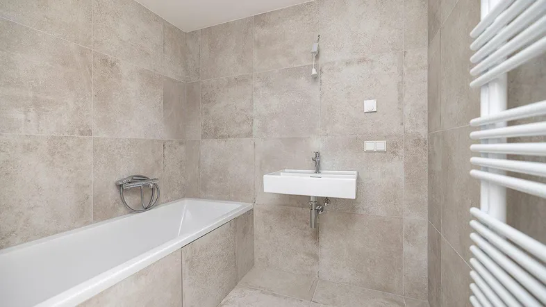 Helles Badezimmer mit Badewanne, Einzelwaschbecken und beheiztem Handtuchhalter.