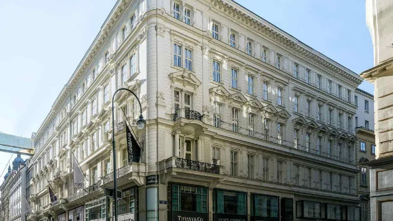 Historisches Gebäude mit klassischer Architektur und Geschäften im Erdgeschoss an einer belebten Straße.