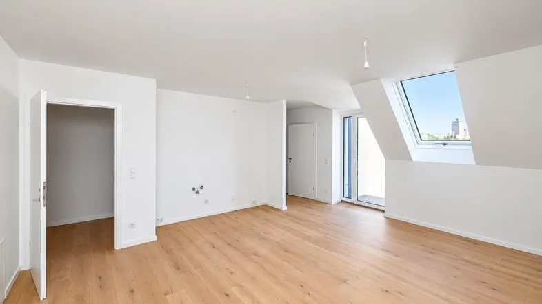Heller Wohnraum im Dachgeschoss mit hochwertigem Parkettboden und großen Dachfenstern.