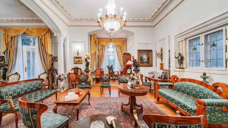 Großzügiges Wohnzimmer mit opulenten Möbeln, Stuckdecken und Kronleuchtern, das aristokratischen Charme versprüht.