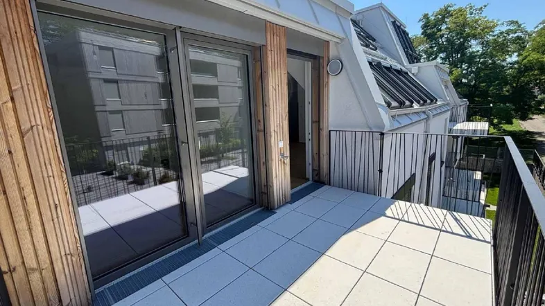Geräumiger Balkon mit modernen Fliesen, Holzverkleidung und weitem Blick ins Grüne.