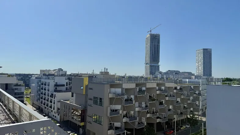 Panoramablick über eine moderne Stadtlandschaft mit hohen Gebäuden und klarem Himmel.