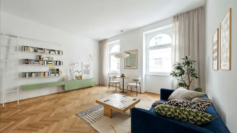 Helles, modern eingerichtetes Wohnzimmer mit Fischgrätparkett, blauer Couch und grünen Regalelementen.
