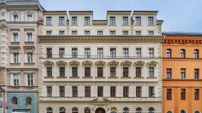 Elegante Fassade eines historischen Gebäudes mit vielen Fenstern und klassischer Architektur an einer Stadtstraße.
