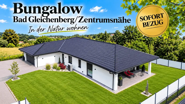 Moderner Bungalow mit dunklem Dach, weißer Fassade, gepflegtem Rasen und kleiner Terrasse in grüner Umgebung.