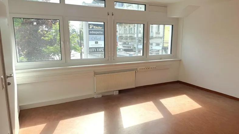 Heller, leerer Raum mit großen Fenstern und Blick auf die Straße, ideal für ein Büro oder Geschäft.