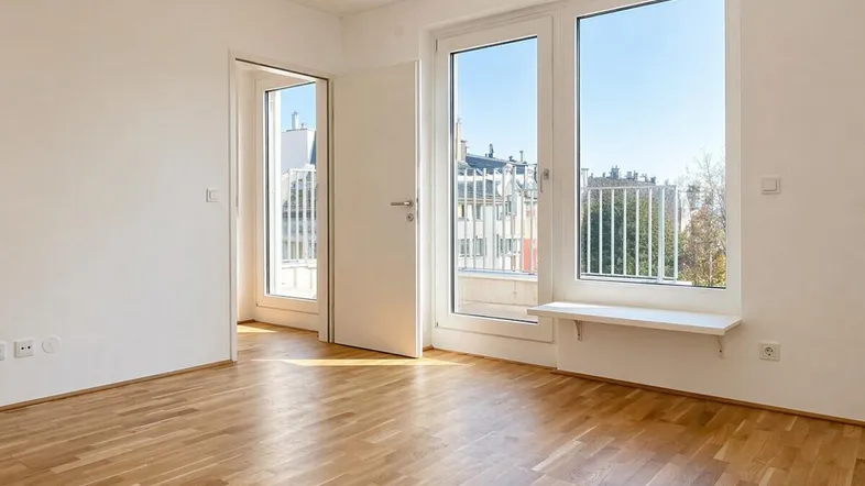 Helles Zimmer mit Parkettboden und Zugang zu einem Balkon, bietet einen weiten Blick über die Stadt.