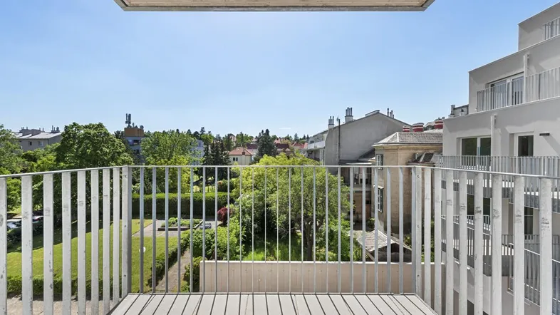 Heller Balkon mit Holzboden und Metallgeländer, bietet einen weiten Blick ins Grüne und auf die umliegende Wohngegend.