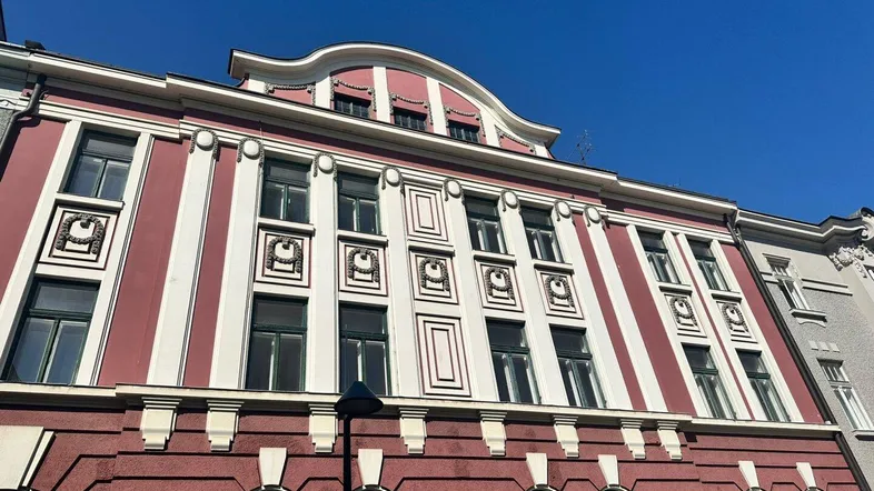 Historische Fassade mit roten und weißen Streifen und dekorativen Elementen unter blauem Himmel.