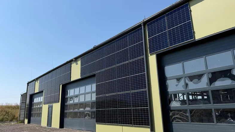 Gebäudefassade mit mehreren Garagentoren und integrierten Photovoltaikmodulen für nachhaltige Energiegewinnung.