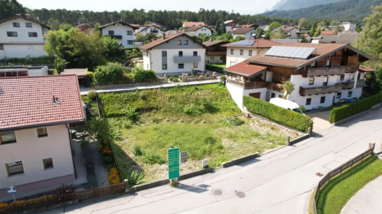 Luftaufnahme eines unbebauten Grundstücks in einer Wohngegend mit Bergblick und umliegenden Häusern.