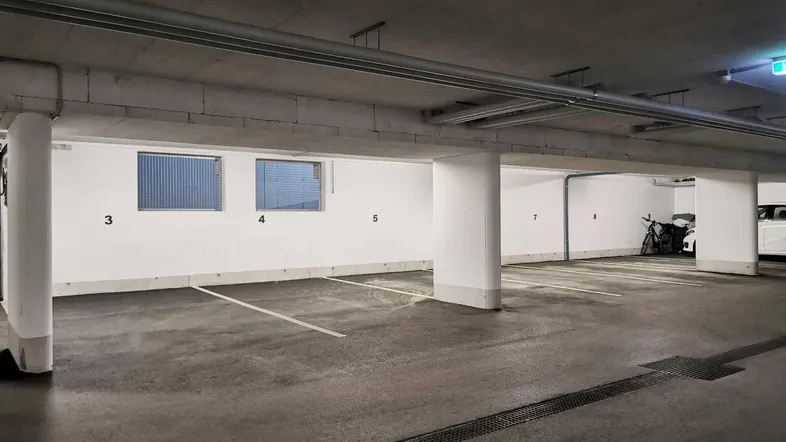 Tiefgarage mit mehreren markierten Stellplätzen und Betonwänden, ideal für Bewohner.
